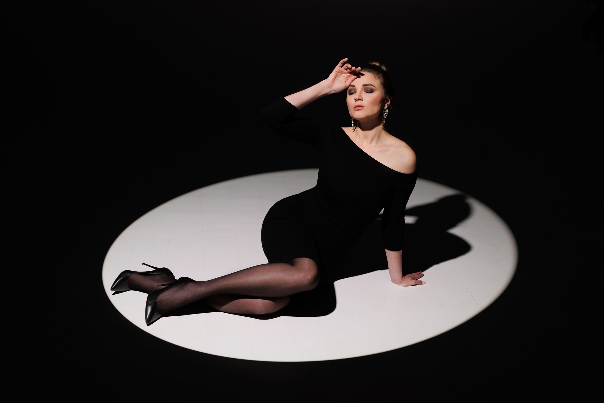 Studio-Kunstfoto einer schönen sexy jungen Frau, einer Geschäftsfrau, die in der Mitte eines Lichtkreises sitzt